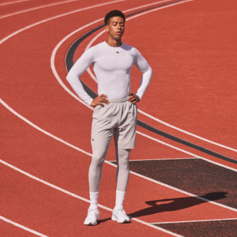 Male model wearing a white coolcore long sleeve white compression shirt and gray shorts.